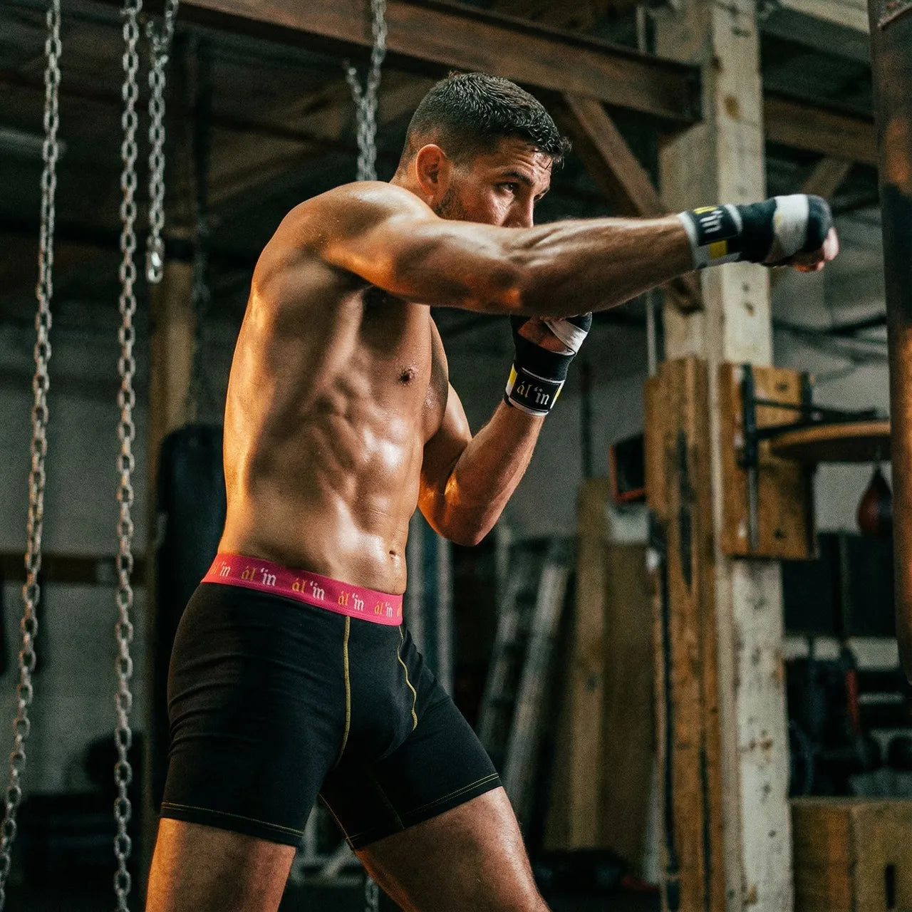 Athlete in a gym wearing boxing gloves and shorts, ready to box.